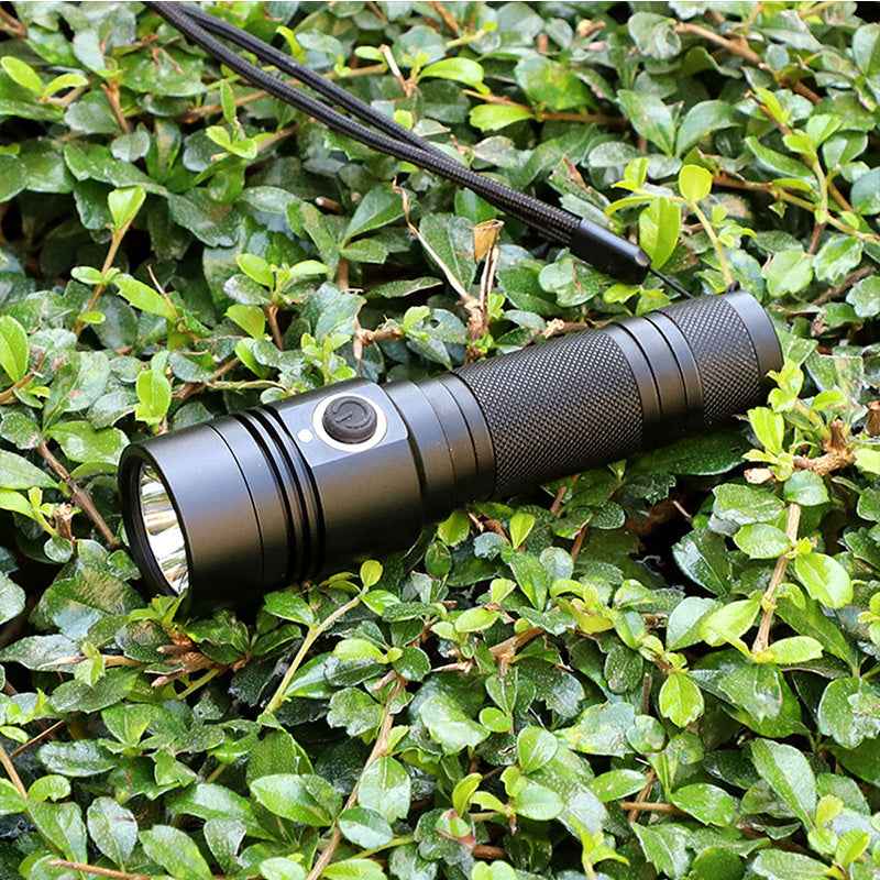 USB rechargeable tactical flashlight with ultra-thick aluminum alloy body on green foliage background
